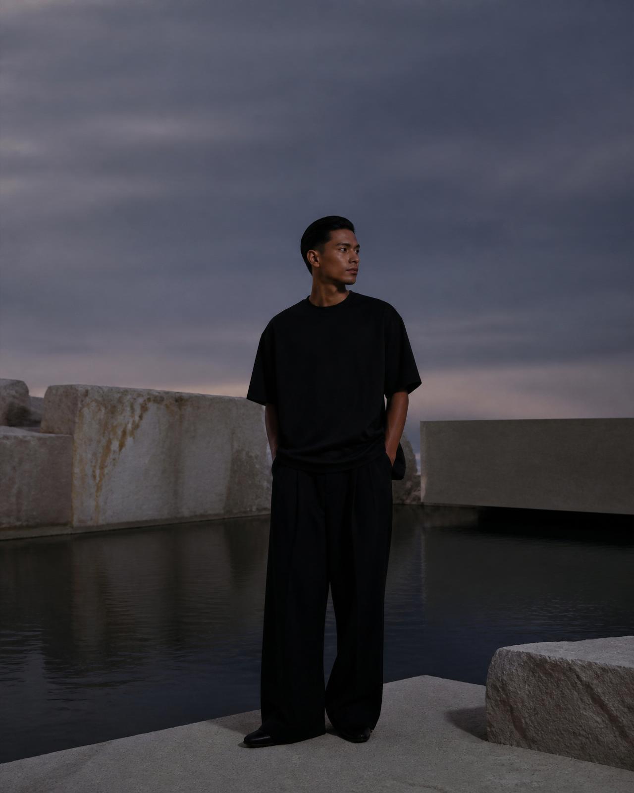 Model in Noir Society black attire beside architectural water landscape